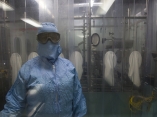 Una operaria de la máquina llenadora en la Planta de Parenterales 2 de Biocen, vista a través del cristal desde el área de recepción de viales. Foto: Irene Pérez/ Cubadebate.