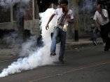 Un partidario del presidente de Honduras, Manuel Zelaya, patea una lata de gas lacrimógeno lanzada por agentes y miembros del escuadrón antidisturbios, que intentan alejar al pueblo del entorno de la Embajada de Brasil en Tegucigalpa