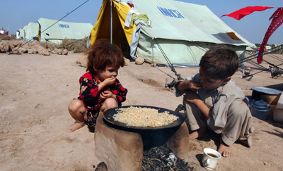Niños paquistaníes comen en un campo de desplazados a las afueras de Peshawar. Más de mil millones de personas padecen hambre en el mundo. - AFP