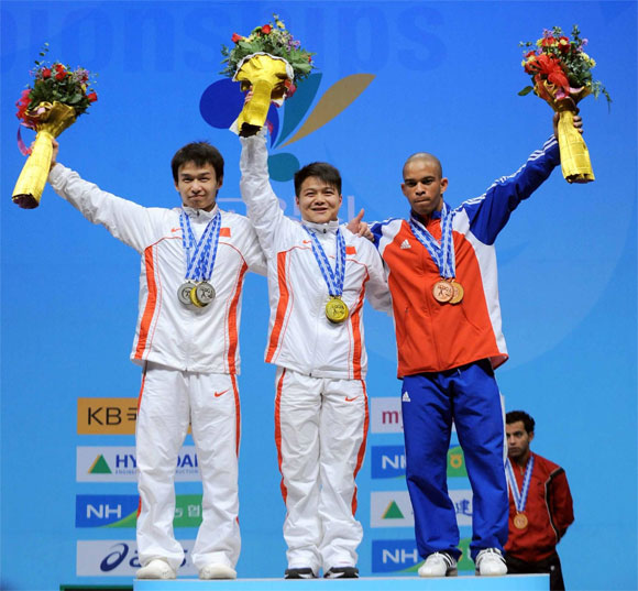 Sergio Alvarez (Derecha), de Cuba, ganador de la medalla de Bronce, en la categoría 56 kg., masculinos, del Campeonato Mundial de Levantamiento de Pesas, realizado en Goyang, al norte de Seúl, capital de Corea del Sur, el 20 de noviembre de 2009. La medalla de oro y de plata fue para los chinos Long Qingquan (Centro) y Wu Jingbiao (Izquierda). Foto: Jung Yeon-Je/AFP
