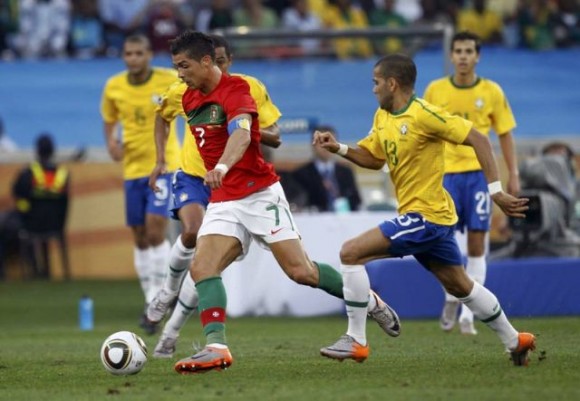 Cristiano Ronaldo (centro) avanzando en el campo frente al jugador brasileño Daniel Alves en el partido Portugal - Brasil que terminó con empate sin goles 