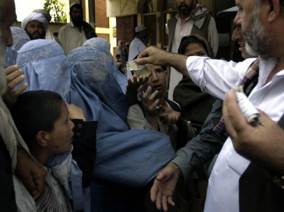 Un afgano da dinero a los pobres en una mezquita el viernes, 3 de septiembre del 2010 en Kabul. Los afganos siguen retirando fondos del mayor banco del país, el Kabul Bank, ante los apuros financieros de la entidad.