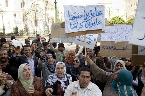 Manifestantes egipcios gritan lemas y portan pancartas con lemas escritos en árabe que dicen ‘Queremos nuestros derechos, queremos nuestra dignidad’, en El Cairo (Egipto), hoy, lunes 14 de febrero de 2011. Cientos de trabajadores gubernamentales se fueron a huelga hoy, durante la tercera jornada sin el régimen de Hosni Mubarak, que renunció a la presidencia el pasado viernes después de casi tres semanas de protestas públicas. EFE/MOHAMED OMAR 