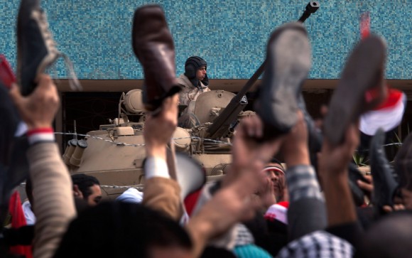 Durante el discurso de Mubarak, los protestantes alzan sus zapatos en señal de ofensa al presidente egipcio. Foto: Boston Globe