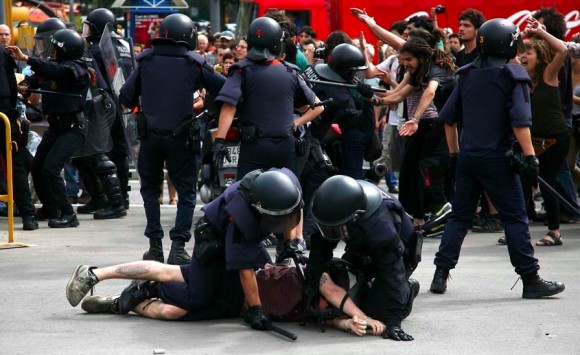 Los mossos reducen a un indignado durante el desalojo de la Plaza Catalunya de Barcelona.