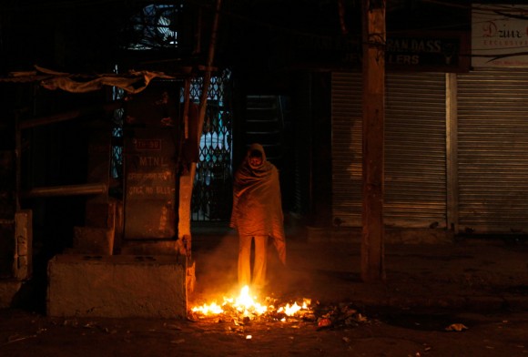 Un hombre sin hogar se mantiene caliente cerca de una fogata en el pavimento en Nueva Delhi, India, 13 de diciembre. (Foto: Mustafa Quraishi / Associated Press)
