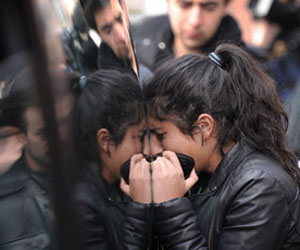 Una joven llora desconsolada junto a un coche fúnebre. Foto: AFP
