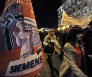 Un grupo de manifestantes pasa junto a un cartel crítico con una publicación alemana antigriega. Foto: Aris Messinis/AFP
