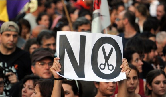 Manifestantes, con un cartel contra los recortes del Gobierno de Rajoy.Foto: AFP.