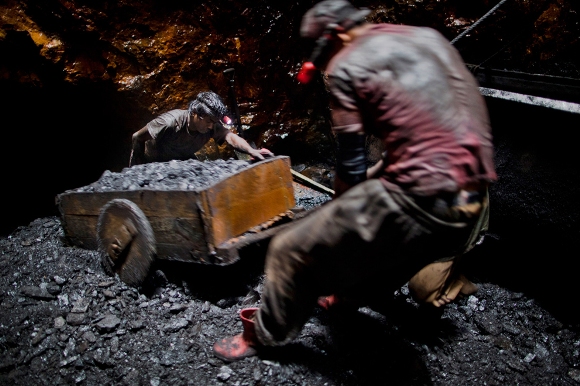 Anil Basnet, de veinte años de edad, empuja un carro de carbón; él y un compañero de trabajo sacan el carbón desde el agujero de ratas de un túnel de 300 pies por debajo de la superficie, el 13 de abril de 2011, cerca del pueblo de Latyrke Lad Rymbai, en el distrito de Jaintia Hills, India. Las colinas Jaintia, ubicadas en el extremo de la India en el estado nororiental de Meghalaya; los mineros descienden a grandes profundidades en las escaleras resbaladizas, de madera desvencijadas. Los niños y adultos se adentran en los agujeros de ratas en los túneles de miles de minas de propiedad privada y no reglamentada, donde realizan la extracción de carbón con sus manos o con herramientas primitivas y sin equipo de seguridad. Los trabajadores pueden ganar hasta 150 dólares por semana o 30.000 rupias por mes.