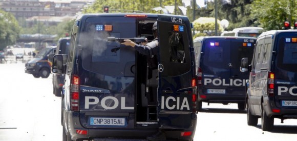 Un agente dispara pelotas de goma contra los manifestantes desde una furgoneta policial.