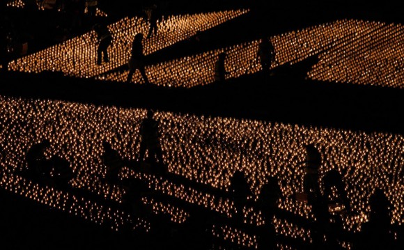 La gente camina en medio de velas encendidas en la Praca do Comercio de Lisboa, el 17 de diciembre de 2011. Cincuenta mil velas fueron encendidas como parte de un intento por parte de la organización no gubernamental Terra dos Sonhos (Tierra de los Sueños) para lograr un récord mundial Guinness. Las velas se venden a 1 euro cada uno ($ 1,30) para recaudar fondos para la realización de los sueños de los niños que sufren de enfermedades largas y terminales. Foto: Reuters / Hugo Correia.