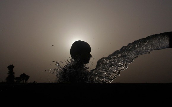 Un niño se refresca en una pipa durante un día caluroso en Faisalabad, Pakistán, el 27 de junio de 2012. La temperatura alcanzó 40 grados Celsius en Faisalabad. Foto: Reuters/Fayyaz Hussain.