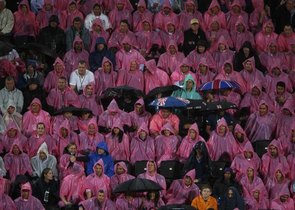 Los espectadores se protegen de la lluvia en la final de voleibol. Foto: Reuters