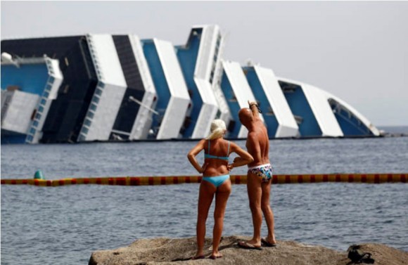 Dos turistas observan el crucero Costa Concordia en el que fallecieron 32 personas