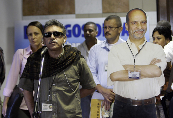 Jesús Santrich, miembro de la delegación de las FARC, junto a una gigantografia del ausente Comandante "Simón Trinidad". Foto: Ismael Francisco/Cubadebate.