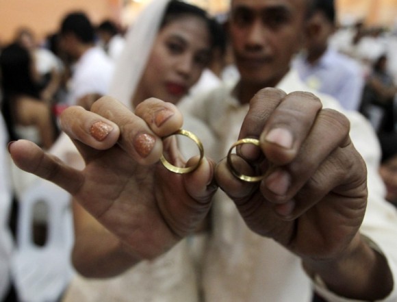 Los recién casados Brandon Balinue (der) y Juie Anne muestran sus anillos durante una boda conjunta en el día de San Valentín, en el ayuntamiento de Taguig, al sur de Manila, en Filipinas. Foto: Francis Malasig / EFE 