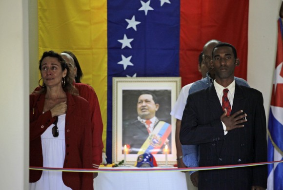 People mourn beside a portrait of the late President Hugo Chavez during a vigil in Venezuela's embassy in Havana