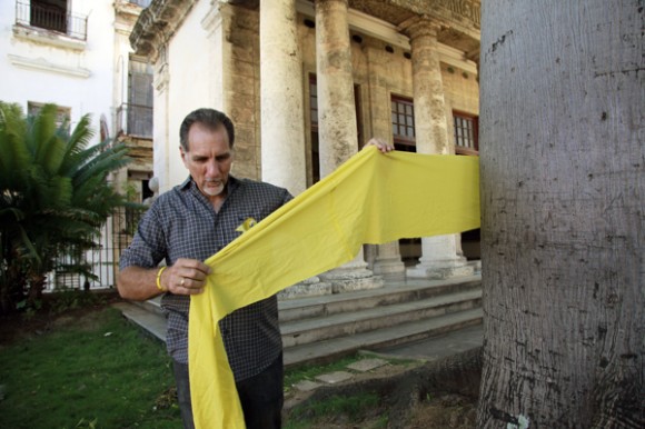René González ata una cinta amarilla a la ceiba de El Templete, en La Habana Vieja. Foto: Roberto Chile/Cubadebate
