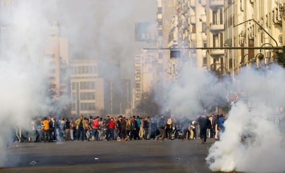 Anti-government protesters and members of the Muslim Brotherhood flee after teargas were fired by riot police during clashes at Ramsis street, which leads to Tahrir Square in downtown Cairo