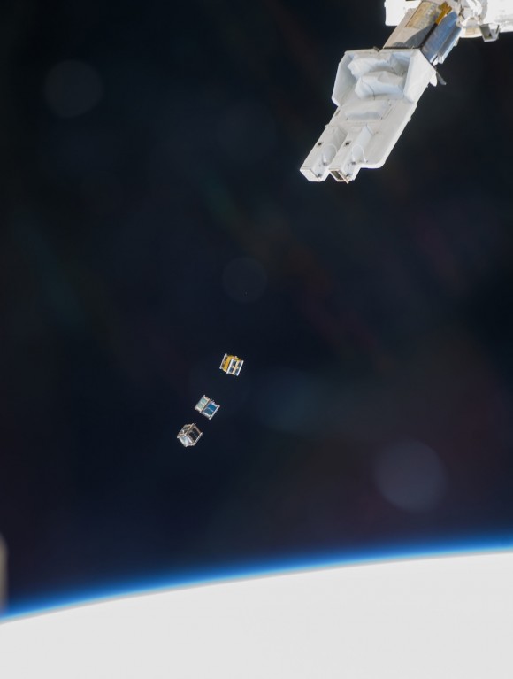 Enmarcado por la Tierra y el enorme mecanismo de la Estación Espacial Internacional, tres CubeSats pequeños (que mide 10 x 10 x 10 cm) son lanzados como dados en el espacio. El brazo robótico japonés Kibo desplegó los satélites pequeños. Con la reducción de la electrónica, tales dispositivos podrían ser cada vez más común en el futuro. Imagen: NASA 