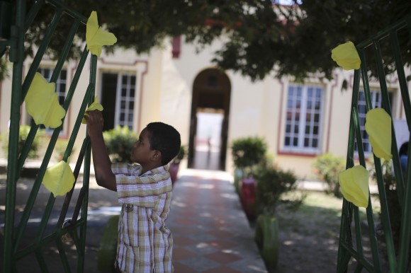 Un niño coloca flores amarillas de papel en la verja de un colegio que funciona en el edificio que acogió la escuela donde el Premio Nobel de Literatura Gabriel García Márquez hizo los estudios primarios, en su pueblo natal de Aracataca, en Colombia. Lunes 21 de abril de 2014. AP Photo/Ricardo Mazalan