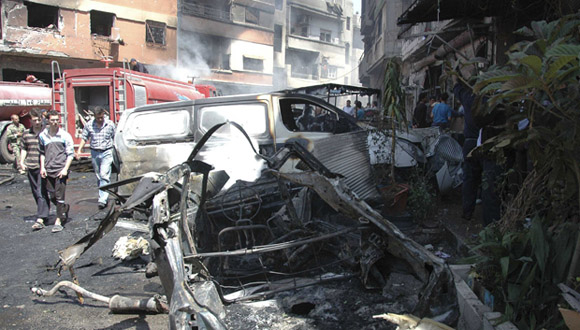 People gather at the site of two car bomb attacks at al-Abassia roundabout in Homs