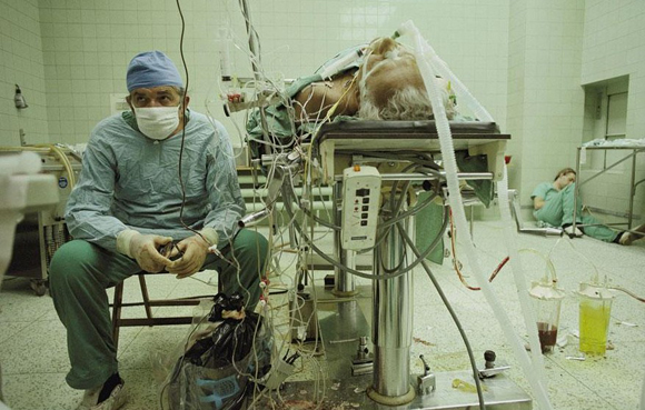 Cirujano del corazón después una operación de transplante de corazón que duró 23 horas, su asistente está en el suelo en un rincón