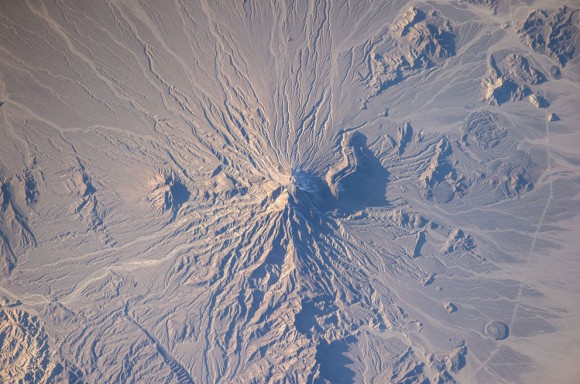 volcán Bazman en Irán aparece en esta imagen fotografiada por un miembro de la tripulación Expedición 38 a bordo de la Estación Espacial Internacional el 5 de enero de 2014. Bazman volcán se encuentra en una región remota del sur dentro del Área Protegida Bazman de Sistan y Baluchestan Provincias. Mientras que el volcán tiene la clásica forma de cono asociado con estratovolcanes , está también fuertemente diseccionada por los canales que se extienden hacia abajo desde la cumbre de 3.490 metros por encima del nivel del mar. Este patrón de drenaje radial - mirando similar a los radios de una rueda de bicicleta - se observa fácilmente en esta fotografía . Estos patrones pueden formar picos simétricos alrededor altas cuando el escurrimiento de agua y la erosión no se ve limitada por la resistencia de los materiales geológicos o barreras para el flujo , provocando esencialmente una distribución uniforme de los canales de escurrimiento de agua alrededor del pico central . (NASA ) 