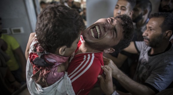 Un palestino llora mientras sostiene el cuerpo muerto de su hermano menor en la morgue del hospital al-Shifa en la ciudad de Gaza el 16 de julio. Su hermano era uno de los cuatro chicos de la familia Bakr muertos en lo que parecía ser el bombardeo naval israelí cerca de la ciudad de Gaza mientras jugaban al fútbol en la playa. Foto: EPA/ Oliver Wiken