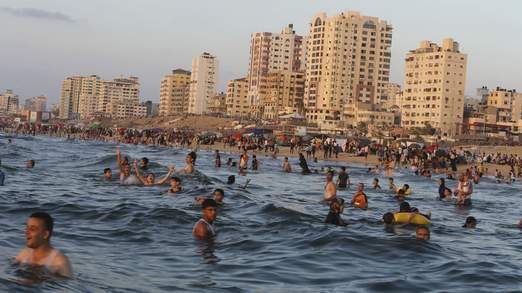 Palestinians swim in the Mediterranean Sea off the coast of Gaza City