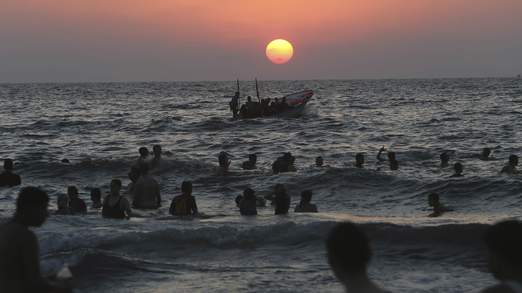 Palestinians swim in the Mediterranean Sea off the coast of Gaza City during sunset