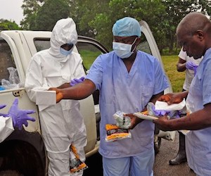 Trabajadores de salud se reparten equipos de protección antes de recoger cadáveres de personas que murieron por ébola en las calles de Liberia