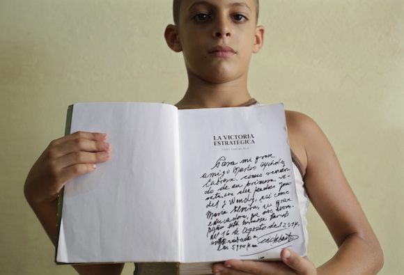 Eight-year-old Marlon Mendez, who claims to be an admirer of Cuba's former president Fidel Castro, shows a book " La Victoria Estrategica" of Fidel Castro dedicated by Castro for him , in San Antonio de los Banos, outside Havana City, August 23, 2014. Cuba's former president Fidel Castro invited him little after he learned about Marlon Mendez who is a bigger admirer from him. REUTERS/Enrique De La Osa (CUBA  - Tags: POLITICS SOCIETY)