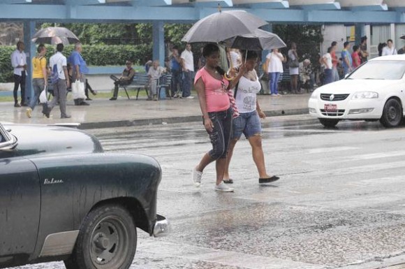 Dos muchachas se protegen de la lluvia mientras cruzan la Calle 23,  en El Vedado,