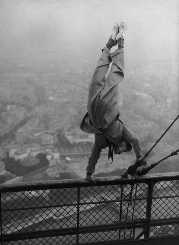 El doble de un actor realiza equilibrios sobre una barandilla de la parte superior de la Torre Eiffel, París, alrededor de 1935.