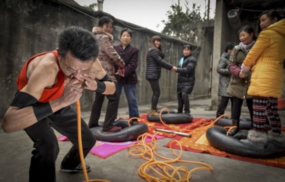 En Chengdu, China, Nie Yongbing infla neumáticos soplando aire por su nariz, mientras que algunas personas se paran sobre ellas. / Foto: elmeme.me