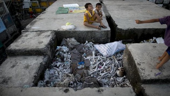 Varios niños juegan junto a huesos humanos en el cementerio público Navotas, de Manila, donde viven / Foto: AFP.