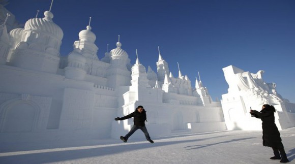 A man jumps to take his souvenir picture in front of large snow sculptures during the Harbin International Ice and Snow Festival in the northern city of Harbin