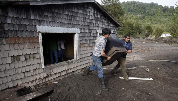 Dos hombres sacan objetos de una casa afectada por la erupción del volcán chileno Calbuco. Foto: EFE.
