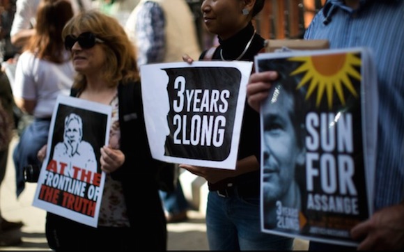Personas se manifiestan en la embajada ecuatoriana donde se encuentra Julian Assange. En una de las pancartas se lee: Sol para Assange. Foto: AP