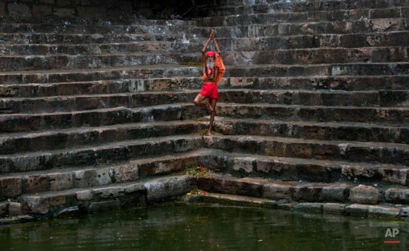 Un hombre santo Sadhu o hindú realiza yoga en las escaleras de Saubhagya Kund, un estanque sagrado, en el templo Kamakhya en Gauhati, India, el martes, 23 de junio de 2015. Cientos de sadhus, hombres santos hindúes o, han llegado para el cinco días del festival para realizar rituales en el templo durante el festival anual Ambubasi que comenzó el lunes. Foto: Anupam Nath/ AP.