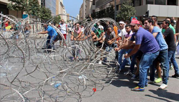 Activistas libaneses intentan quitar el alambre de púas que bloquea la entrada al Palacio de Gobierno del Líbano. Foto: EFE.