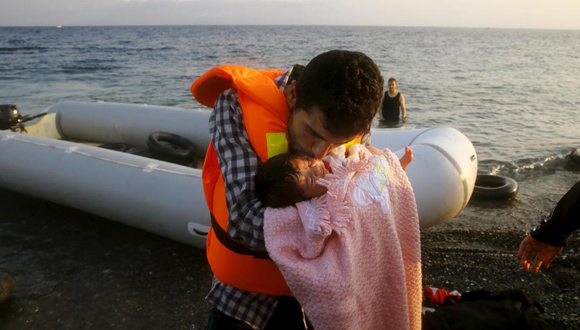 Un refugiado sirio besa a su hija de dos meses al desembarcar en la isla griega de Kos (Reuters)