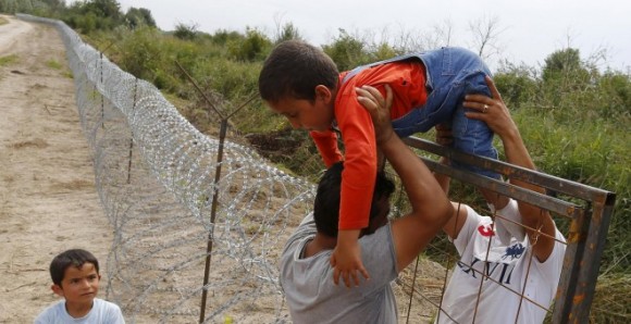 Refugiados kurdos sirios pasan un niño sobre una cerca en la frontera húngaro-serbia, cerca Ásotthalom, Hungría. Foto: Laszlo Balogh/ Reuters.