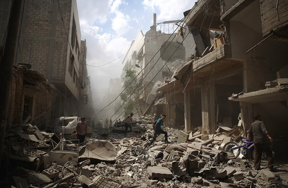 30 de agosto, ciudadanos sirios caminan en medio de los escombros de los edificios destruidos por los ataques aéreos en Douma. Foto: Abd Doumany/AFP.