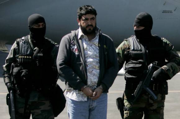 Mexican federal police officers escort Alfredo Beltran Leyva, known as "El Mochomo, upon his arrival at the Mexico City's airport, Monday, Jan. 21, 2008. Beltran was allegedly in charge of transporting drugs, bribing officials and laundering money for the Sinaloa drug cartel, led by Mexico's most-wanted alleged drug lord Joaquin Guzman. (AP Photo/Eduardo Verdugo)