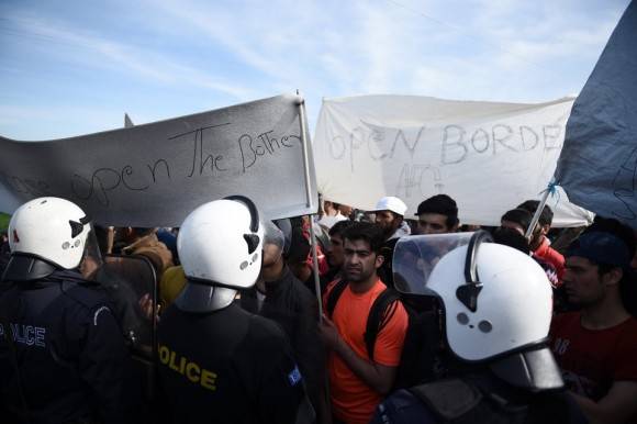 Greek policemen block Afghan refugees before the Greek-Macedonian borderline near the northern Greek village of Idomeni, Monday, Feb. 22, 2016. Greece's government warned Monday it expected a growing number of stranded migrants and asylum seekers after neighbor Macedonia further restricted border access at the weekend. (AP Photo/Giannis Papanikos)