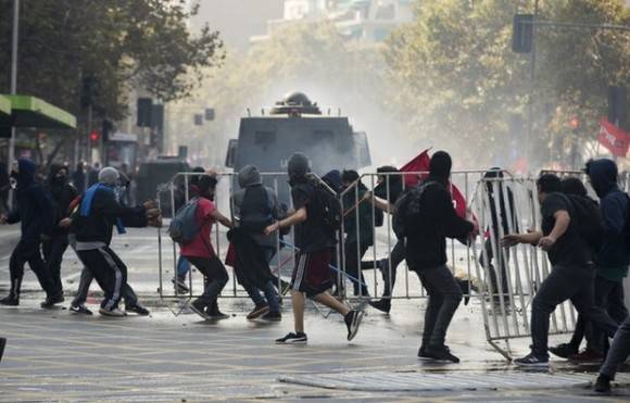 Barricadas incendiarias y la intervención de carros lanza agua de la policía tuvieron lugar en distintos puntos de la manifestación. Foto: AP