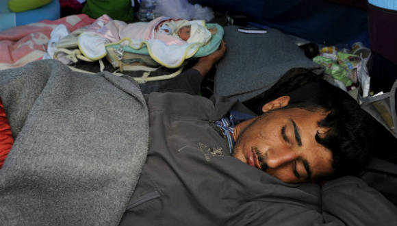 El refugiado sirio Saad duerme junto a su bebé de 10 días, Yasmine, que nació en el hospital de Idomeni (Grecia).  Foto: Reuters